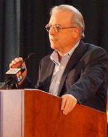 Doug Hoffer standing at a podium with a microphone in his hand